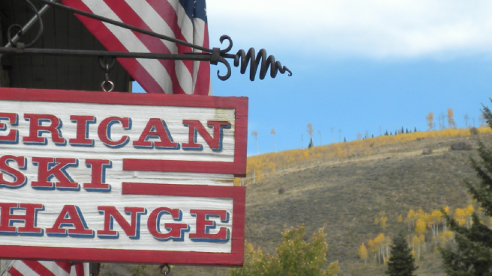 A sign that says American Ski Exchange with an American flag in the background