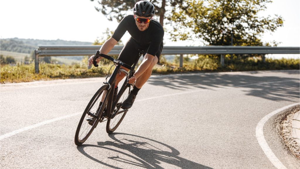  A man in a helmet riding a bicycle from road bike rental on the asphalt road