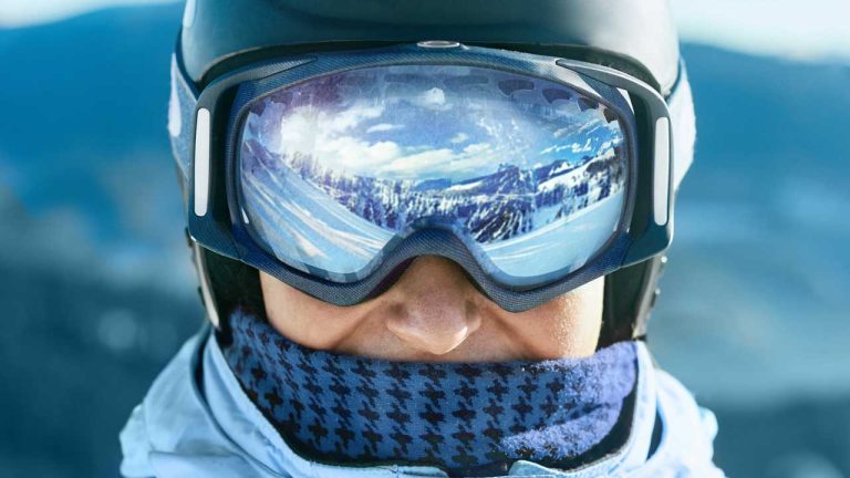 Image of man with reflective ski goggles wearing multiple layers to wear when skiing