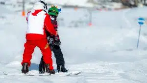 A young boy learns the art of snowboarding under the patient guidance of an experienced instructor.