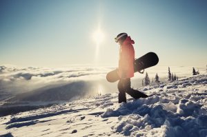 The male stands on the slopes, contemplating which goofy snowboard stance will give him balance.